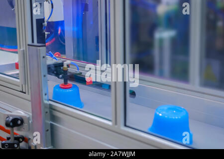 Automatico di produzione robotizzate linea con plastica in movimento vasi blu sul nastro trasportatore Foto Stock