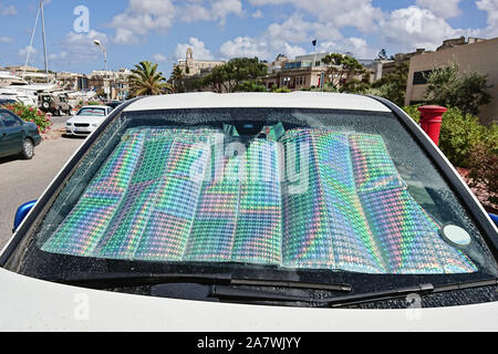 Parabrezza della vettura con protezione solare riflettente superficie interno auto parcheggiate con raggi solari. Metodo per proteggere riscaldata dai raggi del sole all'interno dell'auto Foto Stock