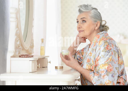 Ritratto di felice donna senior applicare trucco vicino al tavolo Foto Stock