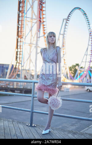 Moda ritratto al crepuscolo di una donna elegante nella parte anteriore del roller coaster Foto Stock