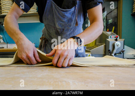 Vista ravvicinata di professional baker lavora l'impasto su una superficie infarinata Foto Stock