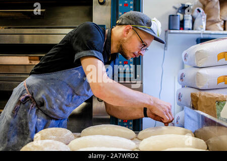 Un professionista baker prepara le pagnotte di pane per andare in forno Foto Stock