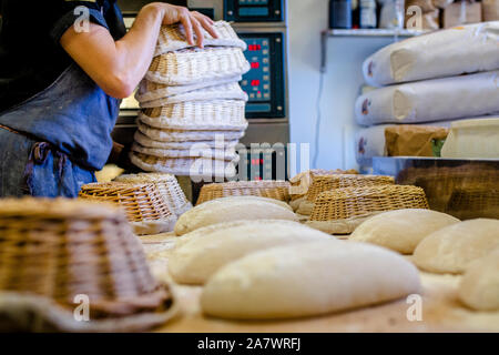 Un professionista di baker con una pila di cesti di pane posti sul contatore Foto Stock
