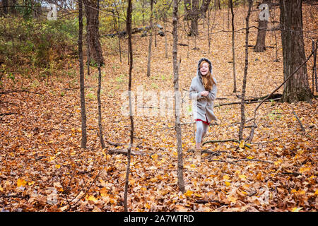 Giovani Capelli rossi ragazza a giocare al di fuori in foglie di autunno Foto Stock