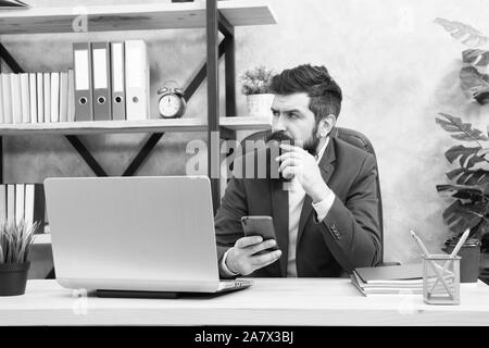 Il boss maschio lavora con lo smartphone. Imprenditore brutale in ufficio. Uomo maturo con barba. barbuto hipster usare il computer. Messaggio di business. Messaggio ai business partner. sempre in contatto. Che cosa abbiamo qui gor. Foto Stock