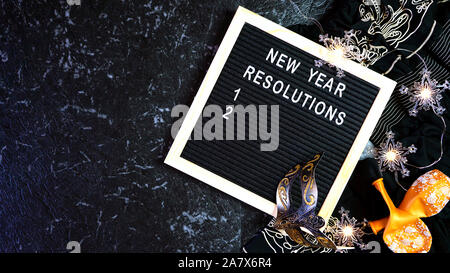 Capodanno risoluzioni flatlay con lettera e bordo nero e oro decorazioni di partito con il polo negativo a copiare lo spazio. Foto Stock