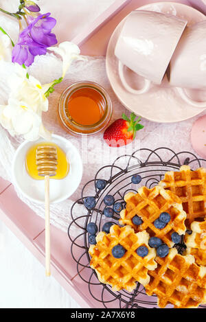 Moderno blush rosa vassoio colazione con cialde, miele e frutta piatto verticale lay close up. Foto Stock