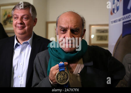 Atene, Grecia. 4 Novembre, 2019. Alekos Fasianos, uno del contemporaneo pittori greci, è visto che mostra la nuova medaglia della maratona di Atene che ha progettato, ad Atene, Grecia, su nov. 4, 2019. La maratona di Atene avrà luogo il 9 novembre 9 e 10 per la trentasettesima edizione. Un nuovo record di 60.000 corridori provenienti da 120 paesi e regioni parteciperanno. Credito: Marios Lolos/Xinhua/Alamy Live News Foto Stock