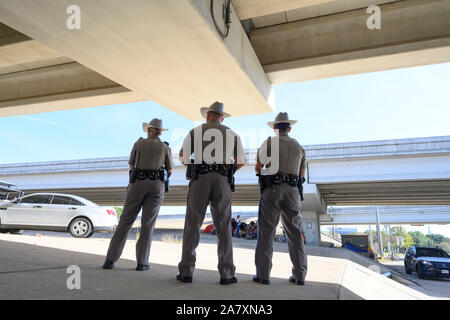 Texas State troopers guarda Texas Department of Transportation appaltatori ripulire un senzatetto encampment sotto un cavalcavia di Austin in Texas, come completano il lavoro ordinato dal Texas Gov. Greg Abbott. Foto Stock