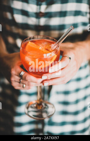 Giovane donna tenendo un bicchiere di Aperol spritz bevanda fredda Foto Stock