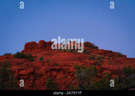 Serata foto di due escursionisti maschio permanente sulla sommità di una roccia rossa collina vicino alla Bell Rock Trail a Sedona. Foto Stock