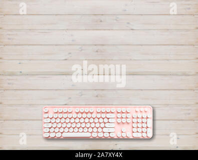 Tastiera per computer rosa con pulsanti bianchi contro lo sfondo di legno, copia spazio, vista dall'alto Foto Stock