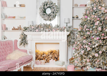 Il design moderno della camera con camino in colori chiari e arredate con albero di Natale e gli elementi decorativi. Nuovo Anno decorazioni, Felice inverno Foto Stock