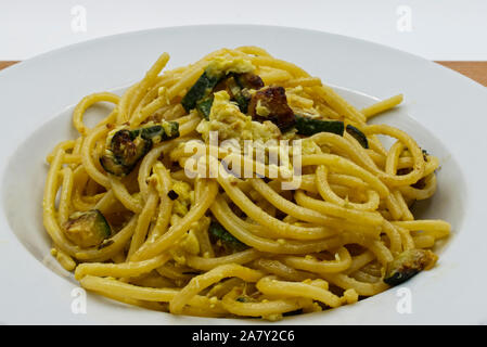 Close-up la pasta alla carbonara di zucchine, carbonara vegetariana, piatto bianco, tavolo in legno Foto Stock