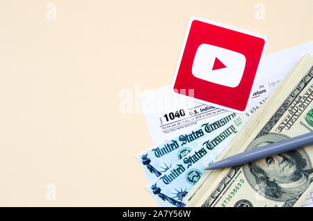 KHARKOV, Ucraina - 3 ottobre 2019: Youtube logo stampato si trova con 1040 singoli redditi modulo con assegno di rimborso e centinaia di fatture del dollaro o Foto Stock