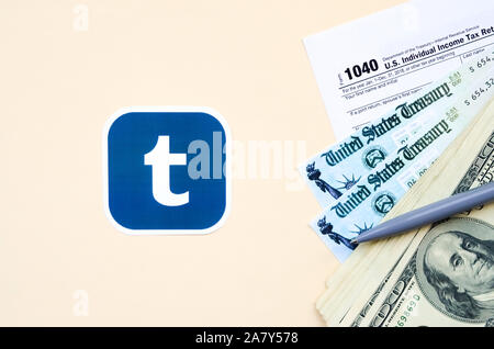 KHARKOV, Ucraina - 3 ottobre 2019: Tumblr logo stampato si trova con 1040 singoli redditi modulo con assegno di rimborso e centinaia di fatture del dollaro sul Foto Stock