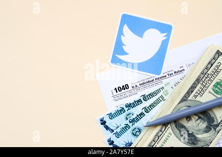 KHARKOV, Ucraina - 3 ottobre 2019: Twitter logo stampato si trova con 1040 singoli redditi modulo con assegno di rimborso e centinaia di fatture del dollaro o Foto Stock