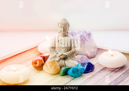 Tutti i sette colori dei chakra pietre cristalli attorno seduti BUDDA STATUETTA IN LEGNO NATURALE vassoio. Equilibrio e calma il flusso di energia nel concetto di casa. Foto Stock