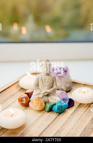 Tutti i sette colori dei chakra pietre cristalli attorno seduti BUDDA STATUETTA IN LEGNO NATURALE vassoio. Equilibrio e calma il flusso di energia nel concetto di casa. Foto Stock