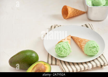 Verde avocado gelato scoop in coni wafle su sfondo bianco. Spazio di copia Foto Stock