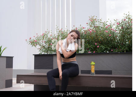 Donna asiatica avente dolore alla spalla quando esercita nel parco. Foto Stock