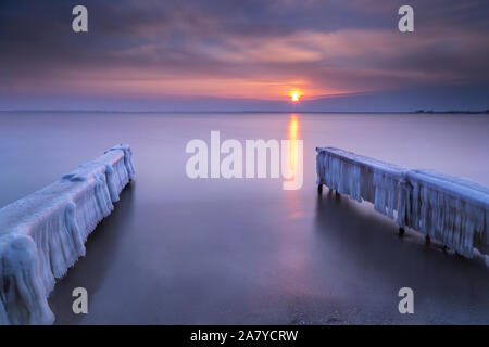 Coperti di ghiaccio pier in mare al tramonto Foto Stock