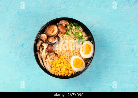 Ramen. Soba Noodles con uova, funghi e ortaggi, overhead shot su uno sfondo blu Foto Stock