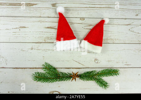 Due cappelli di Babbo Natale sul layout di legno bianco simbolo di sfondo di stare insieme a Natale . Foto Stock