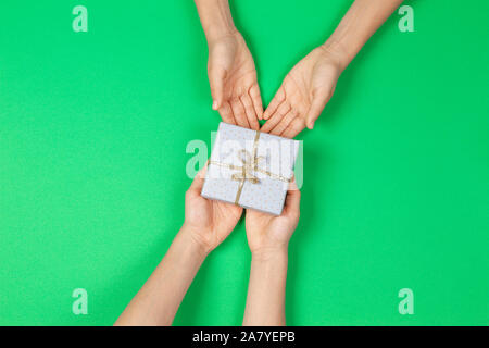 Mani dare presenta caselle su sfondo verde chiaro. Natale, Capodanno, Vacanze, concetto di compleanno Foto Stock