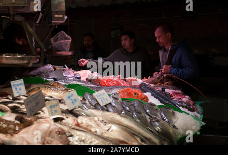 Barcellona, Spagna - 3 Maggio 2017: al Mercado de La Boqueria / mercato La Boqueria. I clienti che acquistano il pesce fresco in un ben fornito mercato del pesce in stallo. Foto Stock