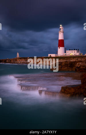 Portland Dorset Inghilterra tempestoso cieli di Portland Bill lighthouse, come onde si infrangono sulla costa rocciosa. Foto Stock