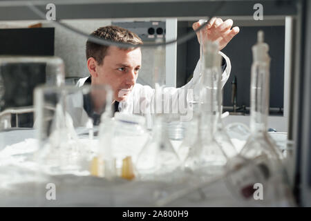 Scienziato maschio conduce esperimenti di chimica in laboratorio di analisi mediche Foto Stock