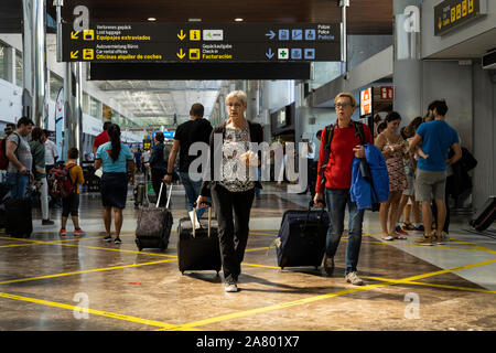 Passeggeri a piedi attraverso il terminal con impennata dei sacchi in Reina Sofia aeroporto di Tenerife Sur, Tenerife, Isole Canarie, Spagna Foto Stock