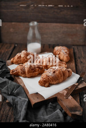 Croissant alle mandorle con crema pasticcera ripieno su uno sfondo di legno. Foto Stock