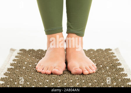 Feets femmina senza scarpe sorge su un tappeto di sport. Foto Stock