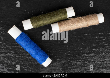 Gruppo di tre tutto il filo per cucire flatlay dello stelo sulla pietra grigia Foto Stock