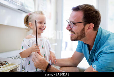 La cura della salute, la vista e il concetto di visione. Bambina scelta di occhiali con padre al negozio di ottica Foto Stock