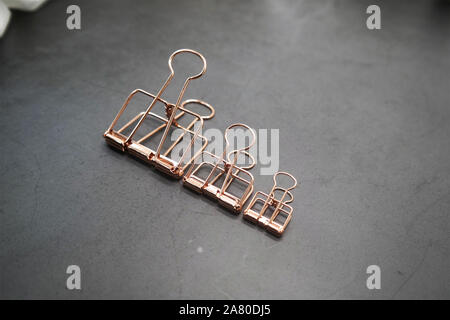 Rose Gold graffe metalliche di 3 sul banco grigio Foto Stock