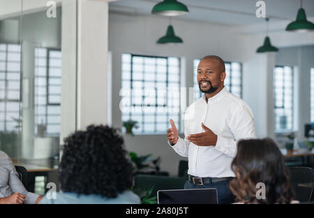 Sorridente African American businessman avente un incontro con il suo team Foto Stock