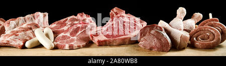 Panorama banner con un assortimento di carne cruda per un barbecue adatto per pubblicità Macelleria con carne di manzo, maiale, pollo, carne di vitello bistecche, costolette e salsicce in un lungo r Foto Stock