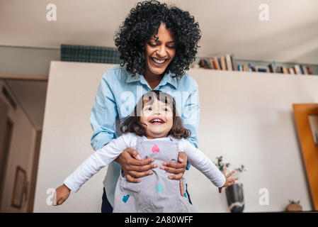 Sorridente giovane madre giocando la sua piccola figlia a casa Foto Stock