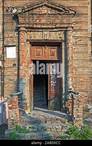 La vecchia porta nella fatiscente casa di mattoni sulla soleggiata giornata calda Foto Stock