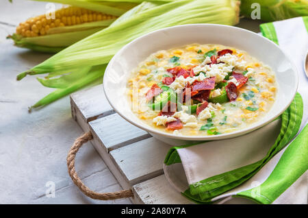 Freschi Fatti in casa la zuppa di mais con pancetta, jalapeno e formaggio di capra in ciotole su grigio chiaro sfondo concreto. Cucina messicana. Foto Stock