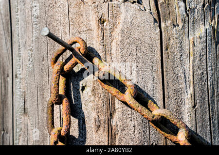 Vecchia catena appesa a un vecchio recinto in legno post Foto Stock