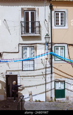 Lisbona, Portogallo : Una donna gesti al di fuori di una tipica casa whiewashed nell'Alfama, il quartiere più antico di Lisbona. Foto Stock