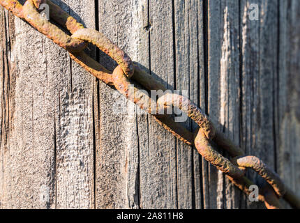 Vecchia catena appesa a un vecchio recinto in legno post Foto Stock