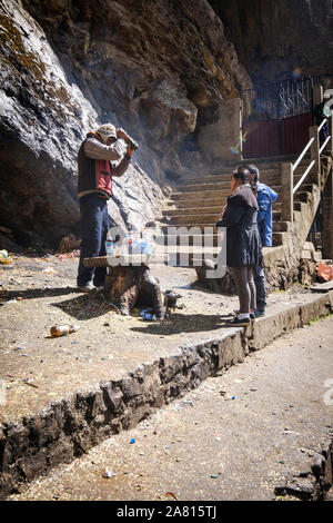 Sciamano di eseguire un sacrificio rituale per un locale giovane alla grotta della Madonna di Lourdes nei pressi di Copacabana, Bolivia Foto Stock