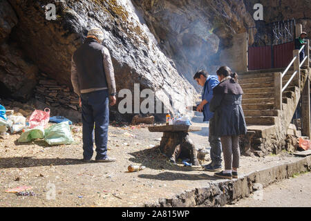 Sciamano di eseguire un sacrificio rituale per un locale giovane alla grotta della Madonna di Lourdes nei pressi di Copacabana, Bolivia Foto Stock