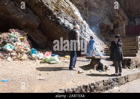 Sciamano di eseguire un sacrificio rituale per un locale giovane alla grotta della Madonna di Lourdes nei pressi di Copacabana, Bolivia Foto Stock