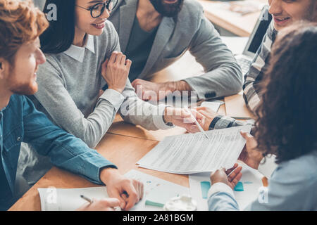 Startupers lavorando insieme in ufficio di affari contratto di lettura gioiosa Foto Stock